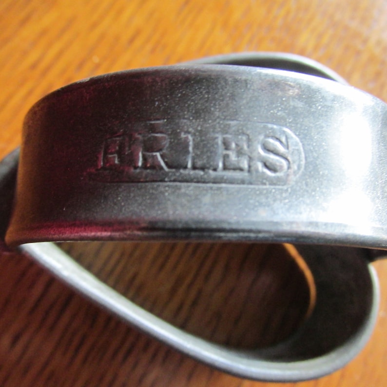 May include: A silver metal cookie cutter in the shape of a heart with the word "ARIES" embossed on the top.