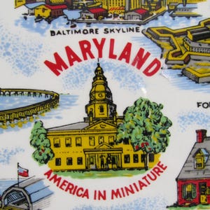 May include: A vintage souvenir plate featuring a colorful illustration of the Baltimore skyline, the Maryland State House, and the text "Maryland, America in Miniature".