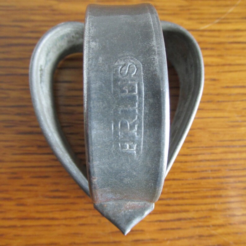May include: A silver metal cookie cutter in the shape of a heart with the word "FRIES" embossed on the front.