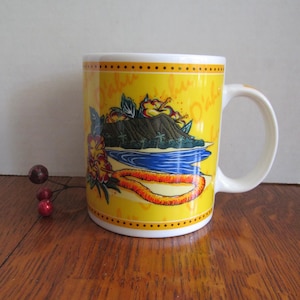 May include: Yellow ceramic mug with a Hawaiian landscape design. The mug features a mountain, ocean, and floral elements. The handle and rim are white, and the mug has a dotted border.