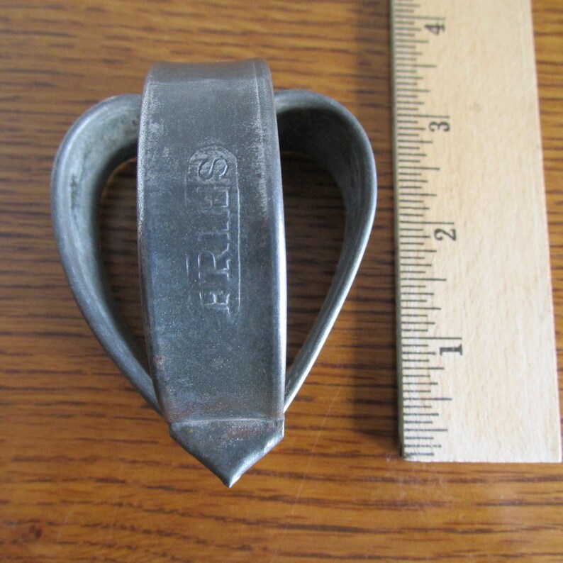 May include: A silver heart-shaped cookie cutter with the word "SPRITZ" embossed on the side.