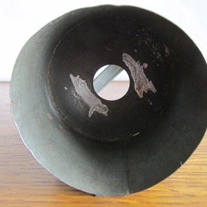 May include: The inside of a metal funnel with a circular opening at the bottom. The funnel is a dark green color and has some rust spots.