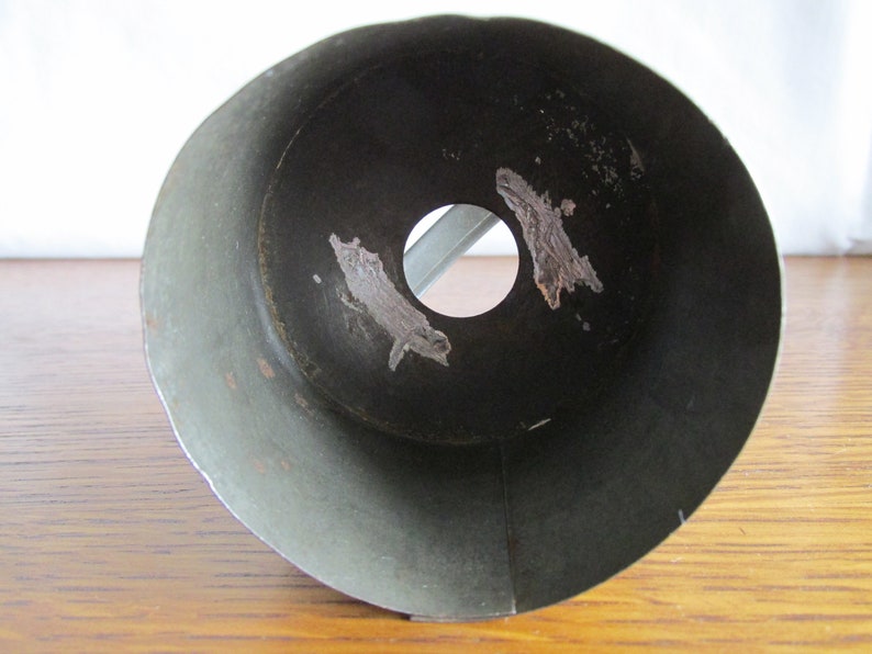 May include: The inside of a metal funnel with a circular opening at the bottom. The funnel is a dark green color and has some rust spots.