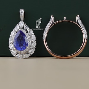 May include: A pear-shaped blue gemstone pendant surrounded by a halo of small white pear-cut stones, paired with a rose gold ring setting featuring pavé-set white stones along the shoulders. The logo BN USA LABDIAMOND JEWELRY is visible.