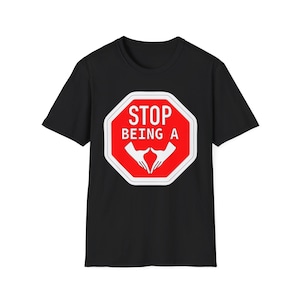 Może przedstawiać: Czarny t-shirt z krótkim rękawem z grafiką czerwonego, ośmiokątnego znaku stop na klatce piersiowej. Znak ma białą obwódkę i biały napis STOP BEING A, umieszczony nad białą grafiką przedstawiającą dwie dłonie ułożone w kształt serca.