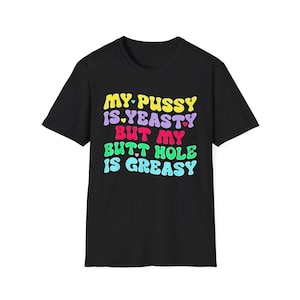 Könnte beinhalten: Ein schwarzes Kurzarm-T-Shirt mit mehrfarbigem Text in einer wellenförmigen Schriftart, der lautet: MY PUSSY IS YEASTY BUT MY BUTT HOLE IS GREASY. Die Grafik enthält kleine Herzsymbole in Gelb, Hellblau, Rot und Pink zwischen den Wörtern.