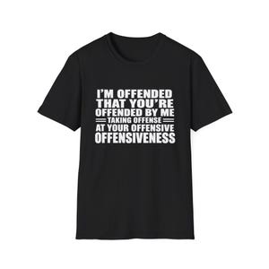 Op de afbeelding: Een zwart t-shirt met korte mouwen en witte tekst die luidt: I'M OFFENDED THAT YOU'RE OFFENDED BY ME = TAKING OFFENSE = AT YOUR OFFENSIVE OFFENSIVENESS. Het shirt heeft een ronde hals en een standaard pasvorm, met de tekst gecentreerd op de borst.