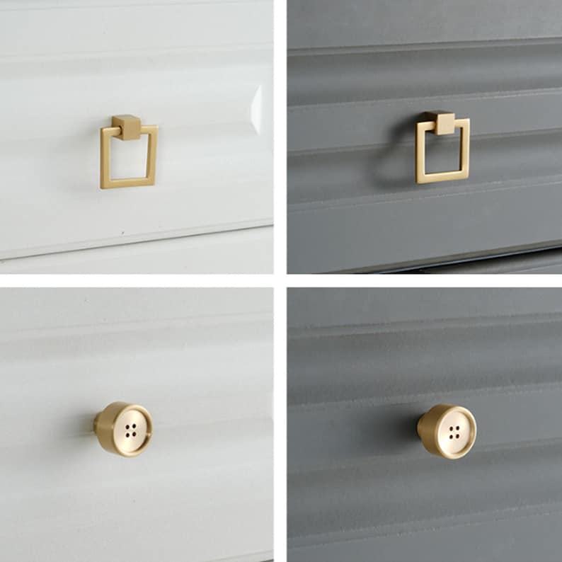 May include: A collection of four gold-toned metal cabinet knobs and pulls. Two feature a square drop-ring design, while the other two are shaped like circular buttons with four central holes, all mounted on white or dark gray drawer fronts.