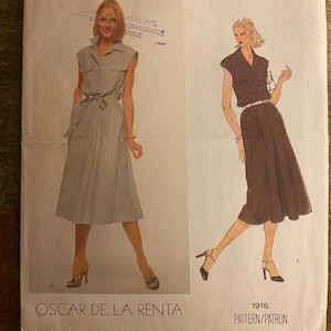 May include: Vintage Vogue American Designer sewing pattern featuring two dress designs by Oscar de la Renta. The pattern shows a sleeveless dress with a collared neckline and a belted waist. The pattern number is 1916.