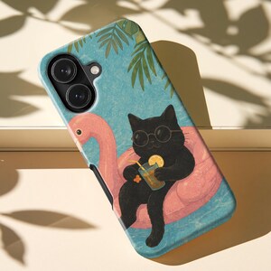 May include: A phone case featuring a black cat wearing round sunglasses, lounging on a pink flamingo pool float in blue water. The cat holds a glass with a yellow straw and a citrus slice. Green palm leaves are visible at the top of the design.