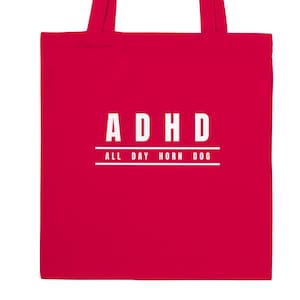 May include: A bright red tote bag featuring white text centred on the front. The text reads ADHD in large capital letters, with the phrase ALL DAY HORN DOG printed in smaller capital letters underneath, framed by two horizontal white lines.