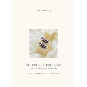 Könnte beinhalten: Ein Buchcover mit dem Titel FLOWER SOAP DESIGN und FLOWER CONFETTI SOAP The Art of Crafting Small Soap Flowers. In der Mitte ist ein quadratisches Bild von zwei cremefarbenen, rechteckigen Seifenstücken mit kleinen lila und grünen Seifenblüten.