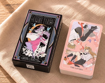Könnte beinhalten: Eine schwarze rechteckige Schachtel mit dem Titel Anime Tarot und einer Illustration einer Figur in rosa-weißem Outfit, daneben ein Kartenstapel mit der Karte Die Liebenden, die zwei Anime-Figuren zeigt, die durch ein rotes Band verbunden sind.