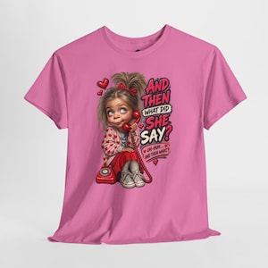 May include: A bright pink t-shirt featuring a graphic of a child with messy hair holding a red rotary telephone. The text reads: AND THEN WHAT DID SHE SAY? UH-HUH... AND THEN WHAT? The design includes small red hearts and a red telephone base.