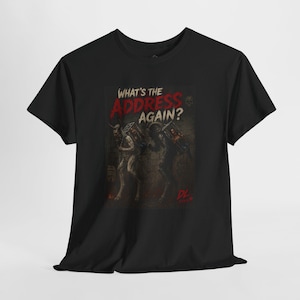May include: A black t-shirt featuring a graphic print of two horned, dark-skinned figures carrying baskets on their backs. The text above reads "WHAT'S THE ADDRESS AGAIN?" in white and red lettering, with the initials "DL" in red at the bottom right.