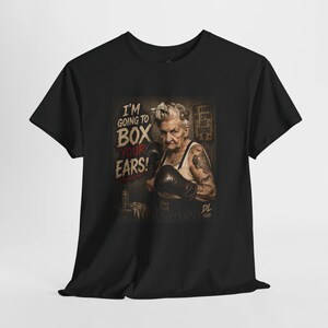 May include: A black t-shirt featuring a graphic print of an elderly person wearing boxing gloves. The text reads I'M GOING TO BOX YOUR EARS! and NO WHINING NO CRYING JUST BOXING. The design includes a small skull icon and the initials DL XXVIII.