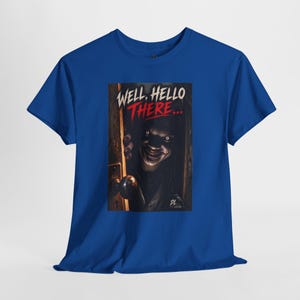 May include: A royal blue short-sleeve t-shirt featuring a graphic print of a dark, shadowy figure peering through a slightly open door. The text "WELL, HELLO THERE..." is printed above the figure in white and red, with "DL" at the bottom.