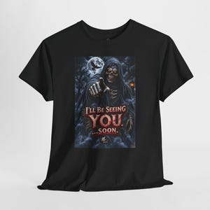 May include: A black short-sleeved t-shirt featuring a graphic print of a hooded skeleton pointing forward. The design includes a full moon, bare trees, and the text I'LL BE SEEING YOU...SOON. The skeleton has glowing red eyes and a dark, eerie aesthetic.