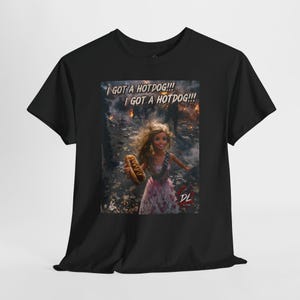 May include: A black short-sleeve t-shirt featuring a graphic print of a doll holding a hotdog in a chaotic, smoky environment. The text "I GOT A HOTDOG!!! I GOT A HOTDOG!!!" appears at the top, with a small "DL" logo in the bottom right corner.