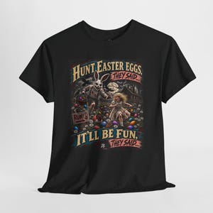 May include: A black t-shirt featuring a graphic illustration of a child running from a sinister rabbit in a field of Easter eggs. The text reads: HUNT EASTER EGGS, THEY SAID... IT'LL BE FUN, THEY SAID... with a sign that says RUN!