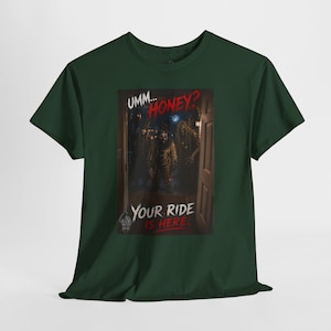 May include: A dark green t-shirt featuring a graphic print of two figures standing in a doorway at night. The text reads UMM... HONEY? YOUR RIDE IS HERE. The design includes a dark, atmospheric scene with a moonlit background and a small logo at the bottom.
