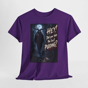 May include: A purple short-sleeve t-shirt featuring a dark forest graphic with a tall, antlered, shadowy figure and the text: HEY! Did you take the last PUDDING? The design includes a full moon, smaller dark figures, and a discarded cup on the ground.