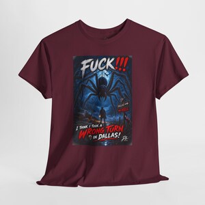 May include: A maroon short-sleeve t-shirt featuring a graphic print of a giant spider looming over a person in a dark forest. The text reads FUCK!!! I THINK I TOOK A WRONG TURN IN DALLAS! with a sign pointing to Dallas and Hell in the background.