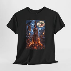 May include: A black short-sleeve t-shirt featuring a graphic print of a person tied to a wooden stake surrounded by fire. A speech bubble above the person reads, "WHY DIDN'T I JUST WASH THE DISHES?" The scene includes a dark sky, a raven, and figures.