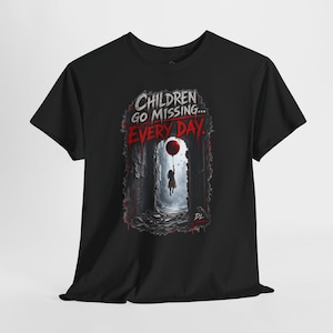 May include: A black short-sleeve t-shirt featuring a graphic print of a dark, narrow alleyway with a silhouette of a person holding a single red balloon. The text reads "CHILDREN GO MISSING... EVERY DAY." in white and red distressed lettering.