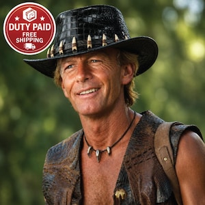 May include: A black crocodile-textured hat featuring a band adorned with multiple white tooth-shaped accents. The hat has a wide brim and a structured crown. A dark cord necklace with three matching white tooth-shaped pendants is also visible.