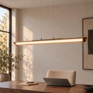 May include: A linear pendant light fixture featuring a long, horizontal, metallic bronze-toned frame with a central, glowing white light diffuser. The fixture is suspended from the ceiling by two thin wires attached to a matching oval canopy.