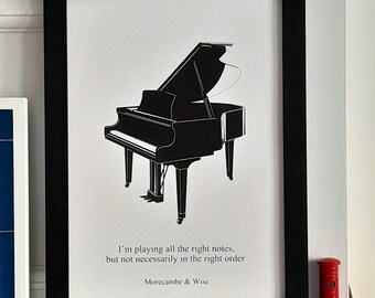 Puede incluir: Una ilustración en blanco y negro de un piano de cola con la cita "Estoy tocando todas las notas correctas, pero no necesariamente en el orden correcto" atribuida a Morecambe & Wise. La ilustración está enmarcada en un marco negro.