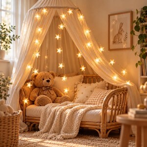May include: A light-colored fabric canopy draped over a rattan daybed, illuminated by strings of warm white star-shaped lights. A brown plush teddy bear sits on the bed, which is layered with a cream-colored knit throw and decorative pillows.