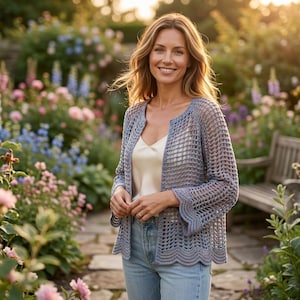 May include: A light blue open-front cardigan featuring a delicate crochet knit pattern with a scalloped hem and three-quarter length sleeves, worn over a simple cream-colored camisole and light-wash denim jeans with a classic button fly closure.