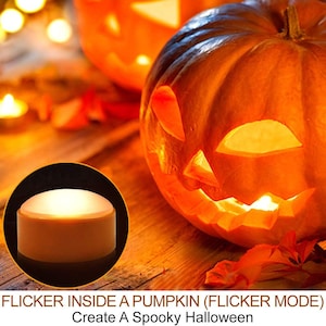 May include: A round, battery-operated LED light with a white dome top and a tan base, shown in a circular inset. The main image features a carved orange pumpkin illuminated from within, creating a warm glow for a Halloween display.