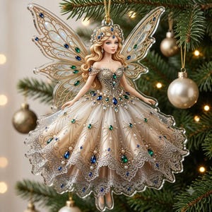 May include: A flat, translucent acrylic Christmas tree ornament shaped like a fairy with long blonde hair, wearing a cream-colored gown adorned with intricate gold filigree, blue and green gemstone accents, and a delicate lace-patterned hem.