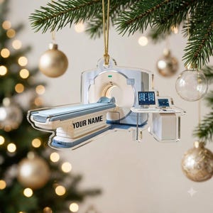 May include: A flat, acrylic Christmas ornament shaped like a CT scanner machine with a patient table, a control console, and two computer monitors. The machine is light blue and white, featuring the black text "YOUR NAME" on the side of the table.
