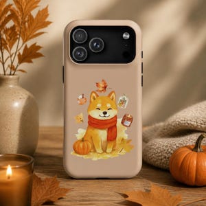 May include: A beige smartphone case featuring a watercolor illustration of a Shiba Inu dog wearing a red scarf, surrounded by autumn elements including a pumpkin, a falling maple leaf, a mug, a small glass bottle, and a candle.