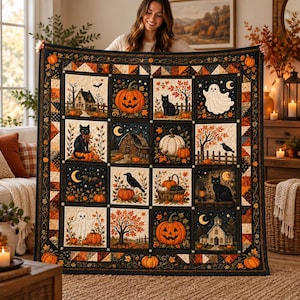 May include: A square quilt featuring a grid of sixteen panels with Halloween-themed illustrations including jack-o'-lanterns, black cats, ghosts, autumn trees, and rustic buildings, all framed by a dark border with orange pumpkin motifs.