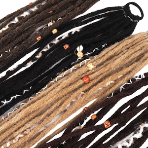 May include: A set of synthetic dreadlocks in shades of black, dark brown, and light brown, secured by a black hair tie. The strands are decorated with various wooden and patterned beads, along with white thread accents wrapped around the hair.