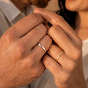 Couple holding hands wearing matching engraved name rings personalized with David and Emma