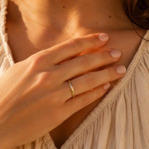 Close-up of a rose gold engraved name ring with the name Maria on a woman's finger