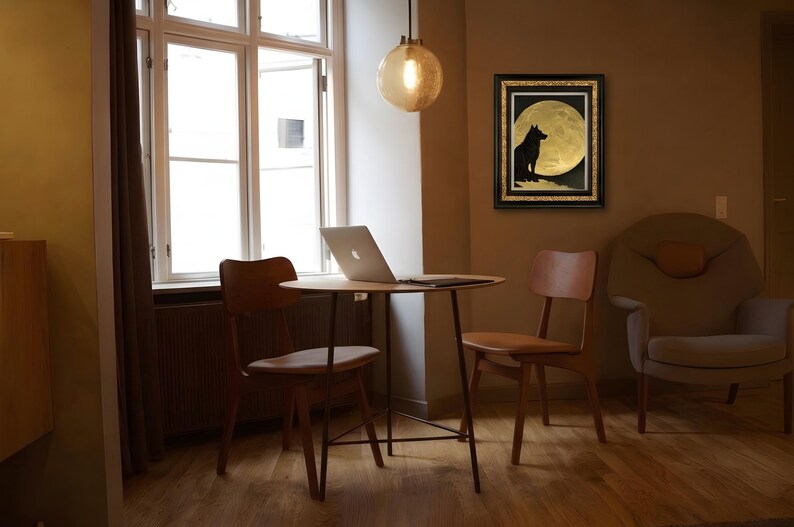 May include: A framed wall art piece featuring a black silhouette of a wolf sitting on a rocky outcrop against a large, textured gold full moon. The artwork is enclosed in a black frame with gold inner detailing, displayed on a wall.