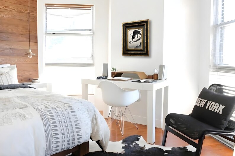 May include: A framed wall art piece featuring a black silhouette of a cat perched on a tree branch against a light background, enclosed in a dark, ornate, multi-layered frame with gold accents, hanging on a plain white wall above a white desk.