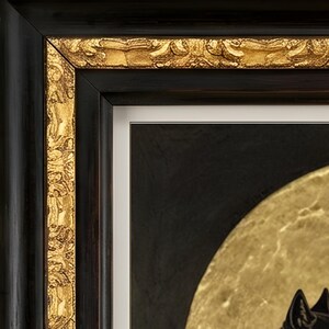 May include: A framed artwork featuring a black and gold color palette. The frame has a smooth black outer edge and an ornate, textured gold inner border. Inside, a white mat surrounds a dark background with a large, circular gold element.