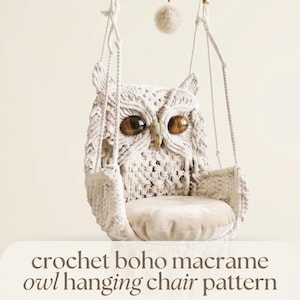 May include: A cream-colored macrame hanging chair shaped like an owl, featuring two large brown tiger eye stone eyes, a pointed beak, and tufted ear details. The chair includes a round seat cushion and is suspended by thick braided ropes.
