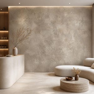 May include: A beige interior space featuring a textured wall, a curved counter with a vase of dried branches, a rounded sofa, and a circular stone coffee table holding a small bowl and a second vase with dried branches under soft lighting.
