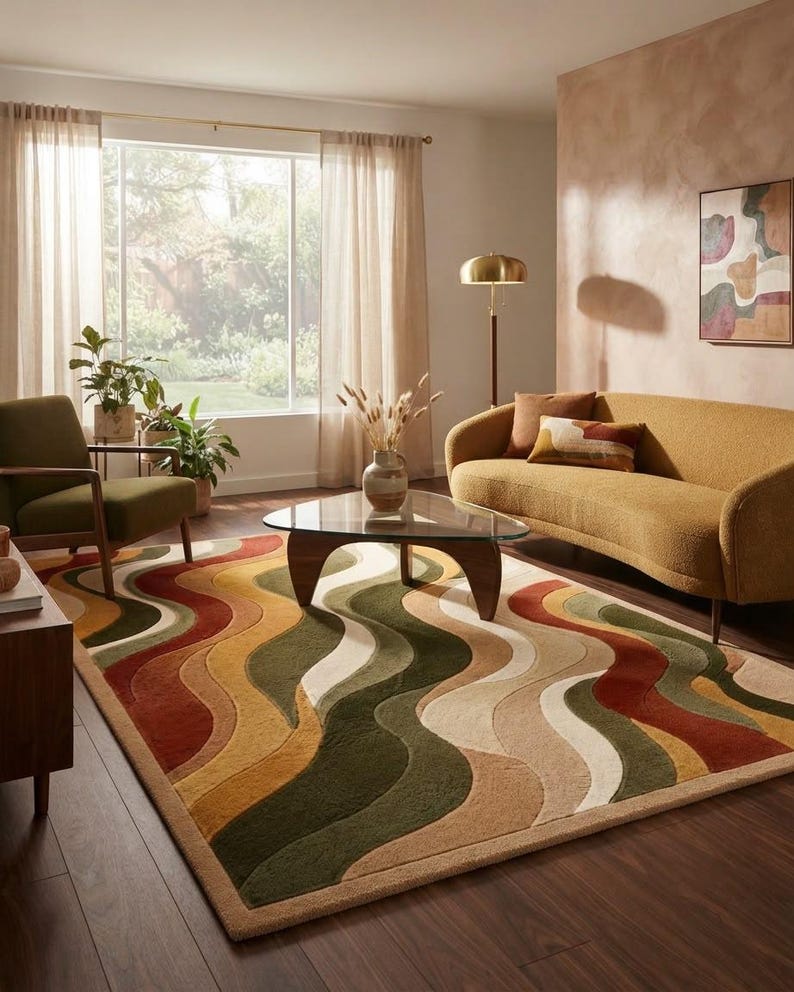 May include: A rectangular area rug featuring a repeating wavy pattern in shades of olive green, mustard yellow, terracotta orange, and cream. The rug has a textured, tufted surface with a solid-colored border, covering a dark wood floor in a room.
