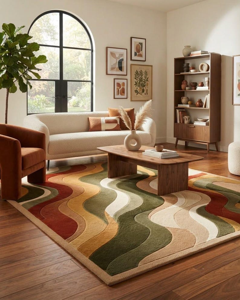 May include: A rectangular area rug featuring a repeating pattern of undulating, wave-like stripes in shades of olive green, burnt orange, mustard yellow, and cream. The rug has a textured, tufted pile surface and is positioned on a wooden floor.