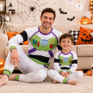 May include: Matching white long-sleeve pajama sets featuring a Buzz Lightyear Space Ranger graphic print with green, purple, and red accents. The tops display the text Space Ranger and Lightyear, while the pants have green cuffs and black details.